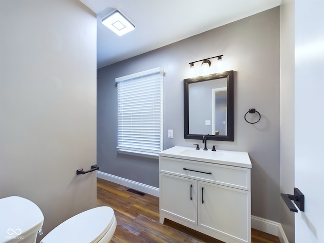 bathroom with toilet, vanity, and hardwood / wood-style flooring