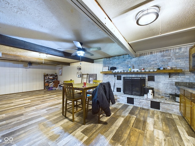 dining room with a fireplace, light hardwood / wood-style floors, a textured ceiling, and ceiling fan