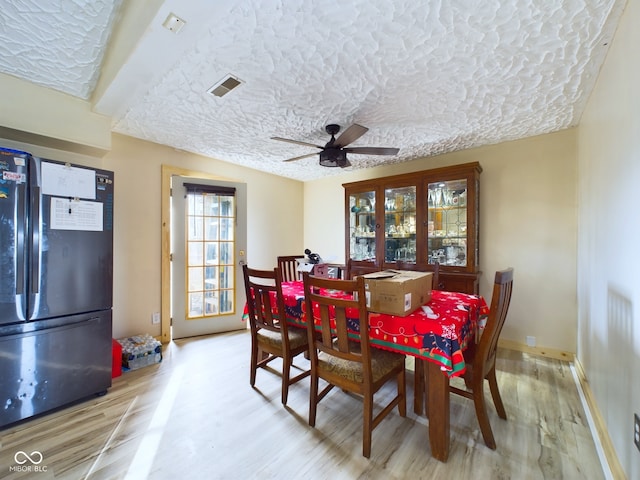 dining room featuring a textured ceiling, light hardwood / wood-style floors, and ceiling fan