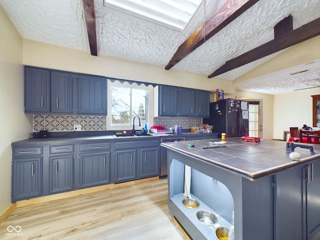 kitchen with dishwasher, black refrigerator with ice dispenser, decorative backsplash, blue cabinetry, and light hardwood / wood-style floors