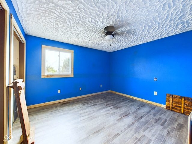 spare room featuring hardwood / wood-style floors and a textured ceiling