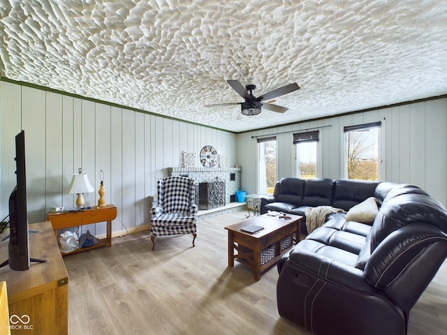 living room featuring hardwood / wood-style floors, a textured ceiling, ceiling fan, and wooden walls