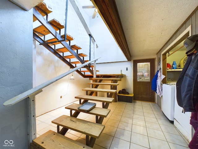 stairway with tile patterned flooring, washer and dryer, and a textured ceiling