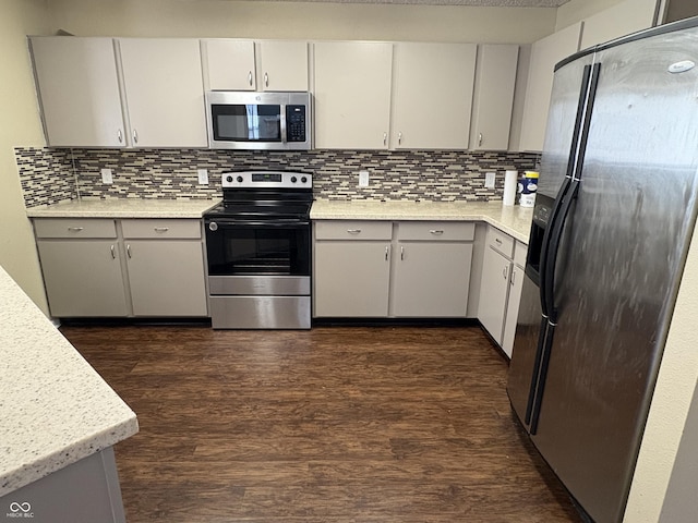 kitchen featuring light stone countertops, decorative backsplash, dark hardwood / wood-style flooring, and stainless steel appliances