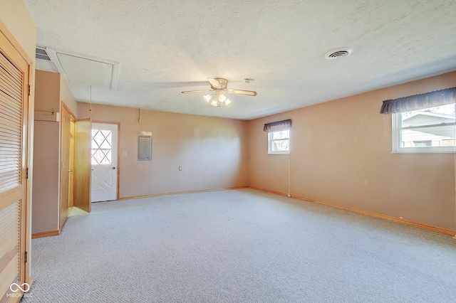 carpeted empty room featuring ceiling fan, a textured ceiling, and electric panel