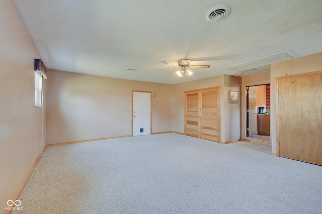 empty room with ceiling fan, light colored carpet, and a textured ceiling