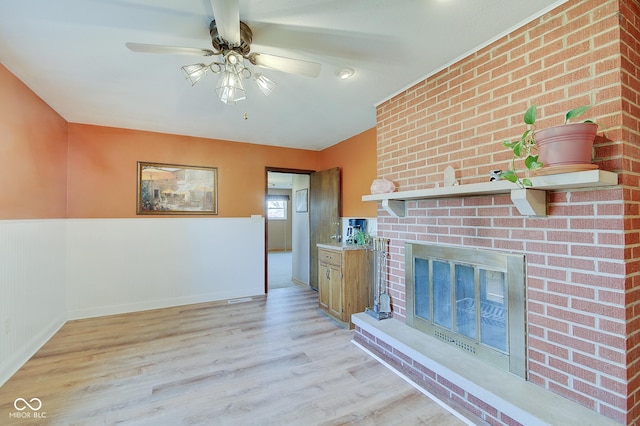 unfurnished living room featuring ceiling fan, a fireplace, and light hardwood / wood-style floors