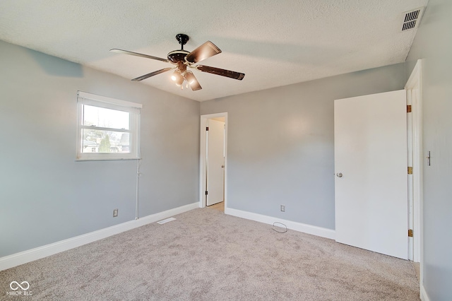 carpeted empty room with ceiling fan and a textured ceiling