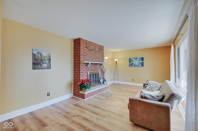 living room with light hardwood / wood-style floors and a brick fireplace