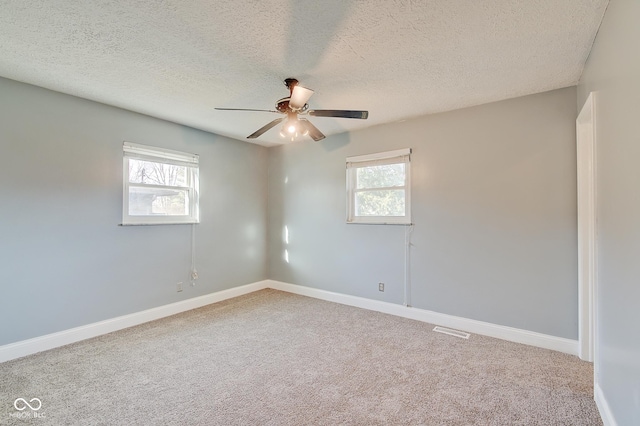 spare room featuring a wealth of natural light, carpet, a textured ceiling, and ceiling fan