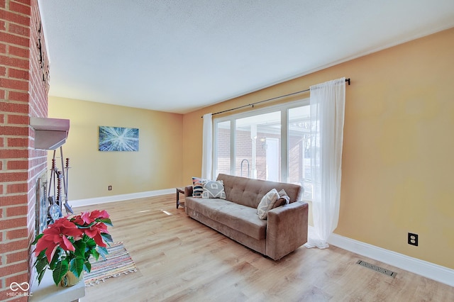 living room with a fireplace, a textured ceiling, and light hardwood / wood-style flooring