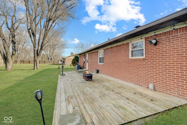 wooden terrace featuring a lawn, cooling unit, and an outdoor fire pit