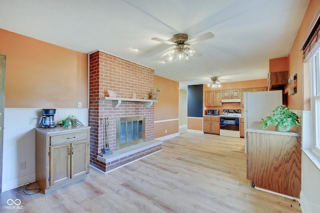 kitchen featuring white appliances, light hardwood / wood-style floors, a brick fireplace, and ceiling fan