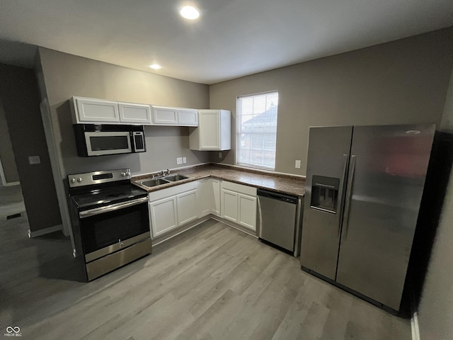 kitchen with sink, white cabinets, stainless steel appliances, and light hardwood / wood-style floors