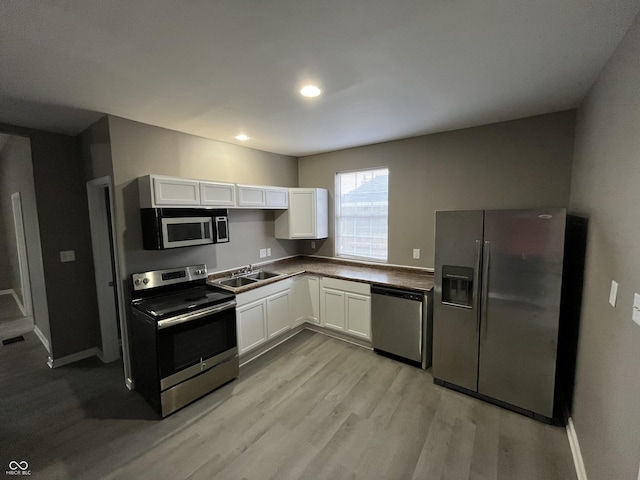 kitchen featuring white cabinetry, sink, stainless steel appliances, and light hardwood / wood-style flooring