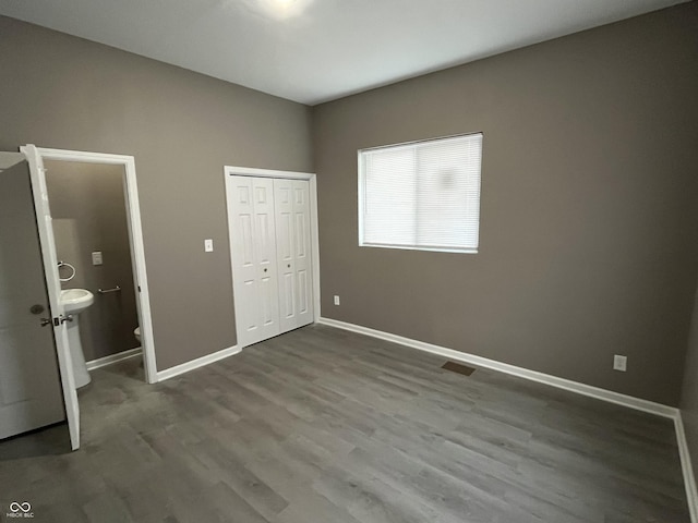 unfurnished bedroom featuring wood-type flooring, connected bathroom, and a closet