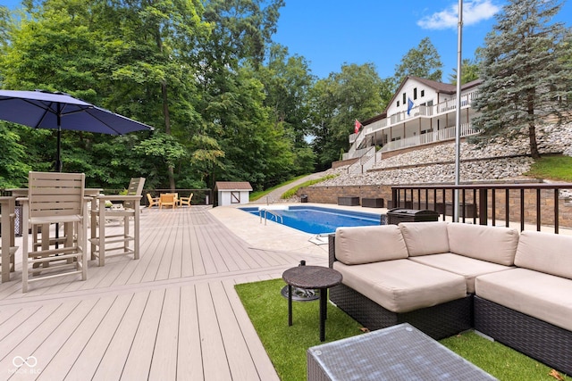 view of pool with a wooden deck, an outdoor hangout area, and a storage shed