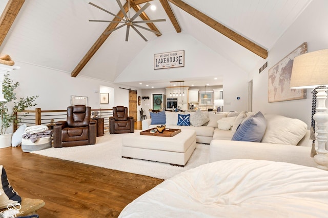 living room featuring beamed ceiling, wood-type flooring, a barn door, and high vaulted ceiling