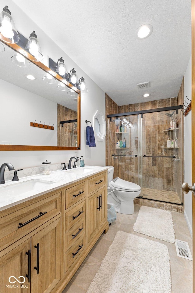 bathroom with vanity, a shower with door, tile patterned floors, toilet, and a textured ceiling