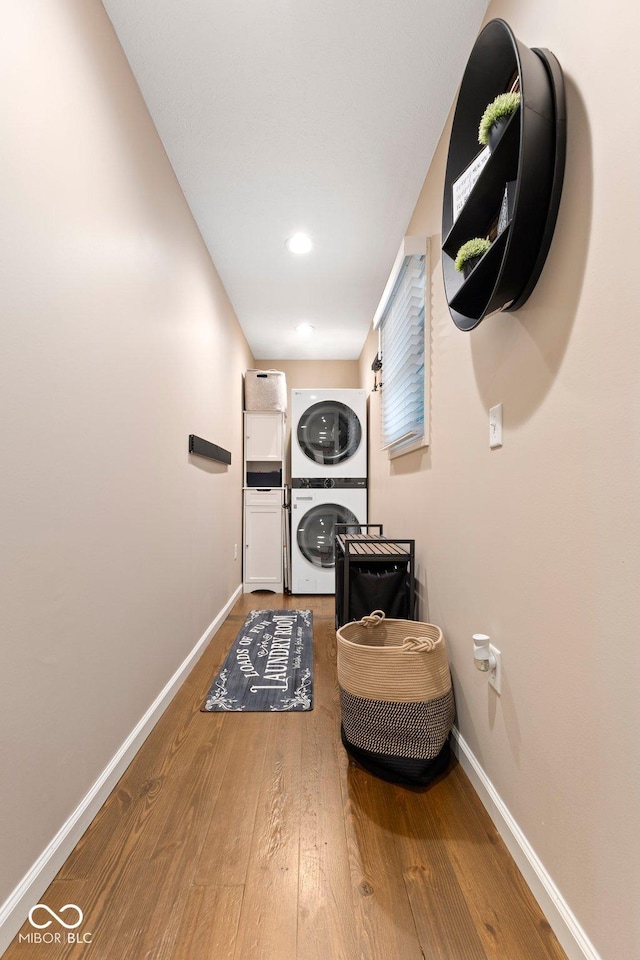 laundry room featuring stacked washer and dryer and hardwood / wood-style flooring