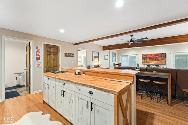 kitchen featuring beam ceiling, ceiling fan, butcher block countertops, white cabinets, and light wood-type flooring