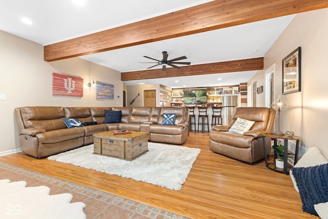 living room featuring beamed ceiling, light wood-type flooring, and ceiling fan