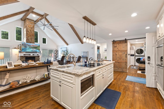 7701 Center Lake Rd, Nineveh, IN 46164 - kitchen featuring stacked washer and clothes dryer, stainless steel microwave, black electric cooktop, a barn door, and a ceiling fan