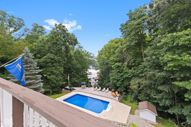 view of swimming pool with a storage shed and a deck