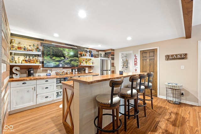 bar featuring white cabinetry, stainless steel fridge, light hardwood / wood-style flooring, and wooden counters