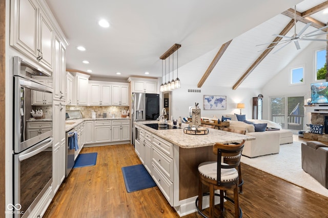 kitchen with pendant lighting, a kitchen breakfast bar, an island with sink, light hardwood / wood-style floors, and white cabinetry