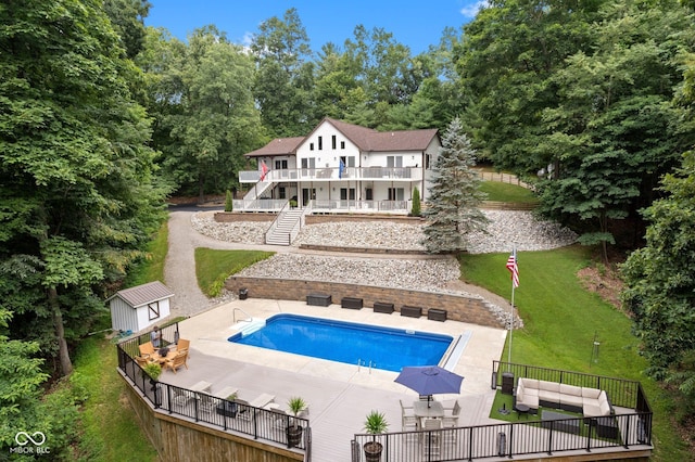 rear view of house featuring a fenced in pool, a patio area, an outdoor hangout area, and a storage shed