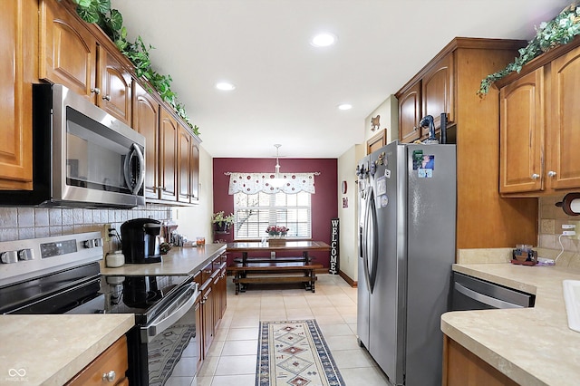 kitchen with tasteful backsplash, pendant lighting, stainless steel appliances, and a notable chandelier