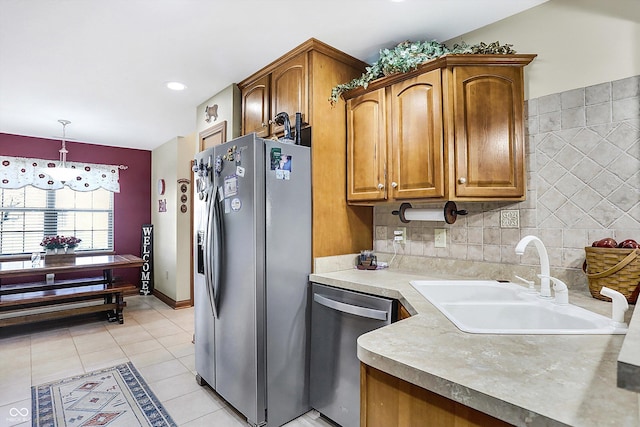 kitchen featuring sink, hanging light fixtures, backsplash, light tile patterned floors, and appliances with stainless steel finishes