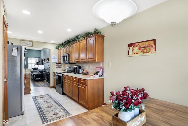 kitchen with decorative backsplash, light tile patterned flooring, and stainless steel appliances