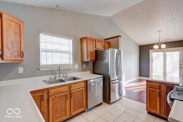 kitchen featuring appliances with stainless steel finishes, light wood-type flooring, vaulted ceiling, sink, and pendant lighting