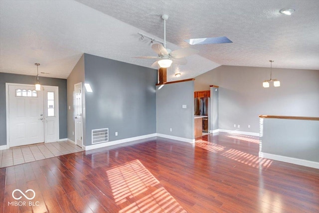 unfurnished living room featuring lofted ceiling with skylight, a textured ceiling, and hardwood / wood-style flooring