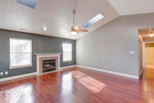 unfurnished living room with a textured ceiling, dark hardwood / wood-style flooring, lofted ceiling with skylight, and a wealth of natural light