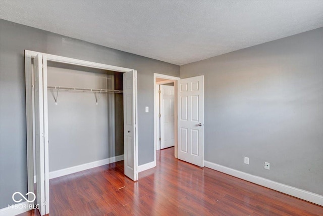 unfurnished bedroom with dark hardwood / wood-style floors, a textured ceiling, and a closet