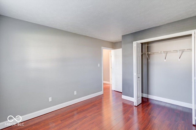 unfurnished bedroom featuring a textured ceiling, dark hardwood / wood-style floors, and a closet