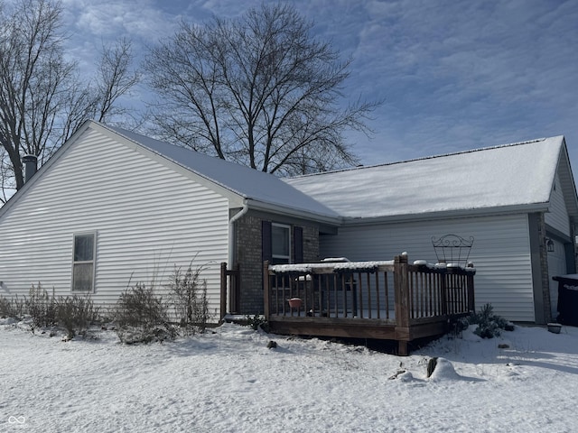 snow covered rear of property with a wooden deck