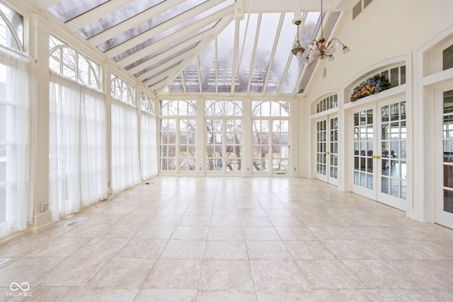 unfurnished sunroom with beam ceiling, french doors, a healthy amount of sunlight, and a notable chandelier