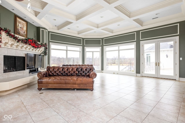 tiled living room with french doors, ornamental molding, coffered ceiling, a tile fireplace, and beam ceiling