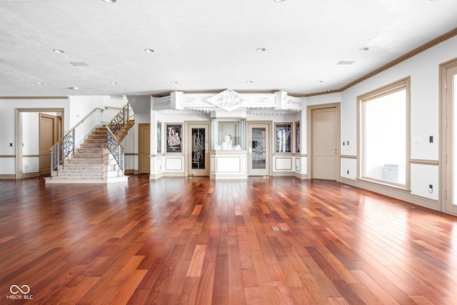 unfurnished living room with hardwood / wood-style flooring and crown molding