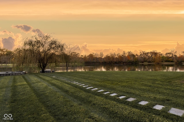 yard at dusk featuring a water view