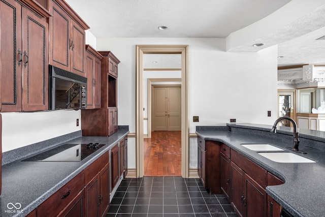 kitchen with sink, dark tile patterned floors, black appliances, and a textured ceiling