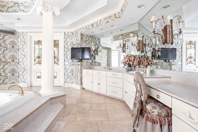 bathroom with decorative columns, vanity, a tray ceiling, crown molding, and a bathing tub