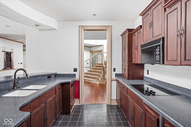 kitchen with black appliances, dark tile patterned floors, and sink