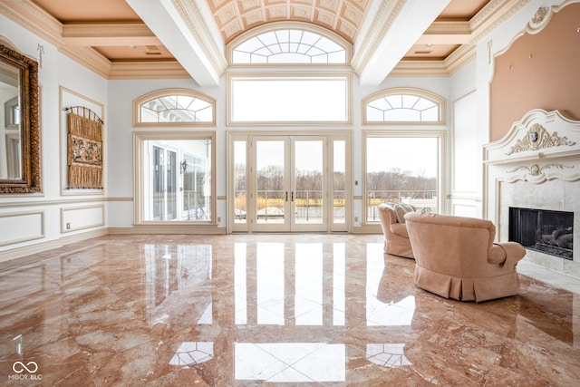 unfurnished living room with a high end fireplace, a high ceiling, french doors, and ornamental molding