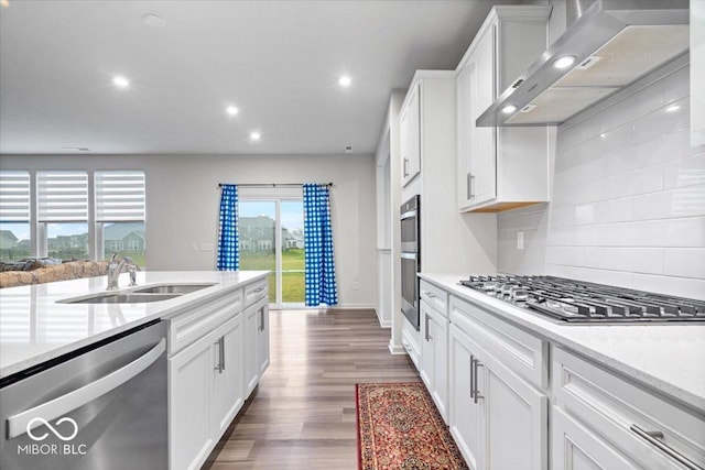 kitchen with appliances with stainless steel finishes, white cabinetry, wall chimney exhaust hood, and sink