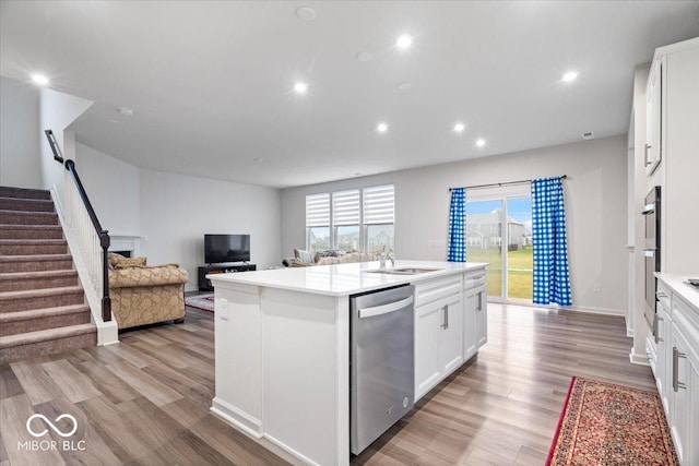 kitchen featuring white cabinets, sink, an island with sink, light hardwood / wood-style floors, and stainless steel appliances